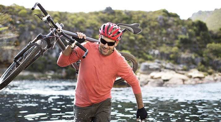 Man carrying bike through water