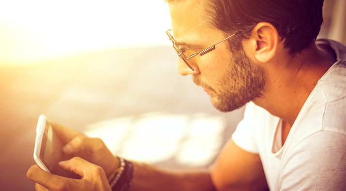 Man with glasses using device in sunlight